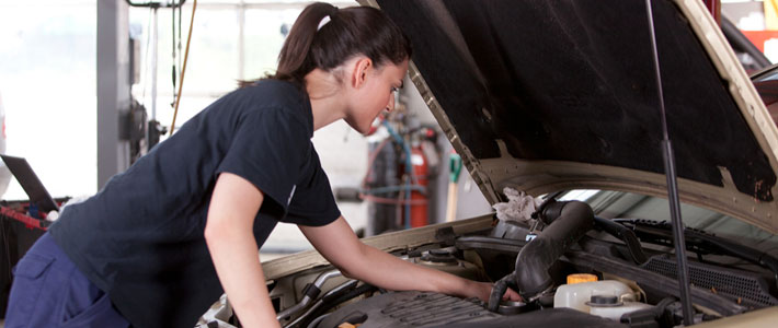 Female mechanic working on car engine